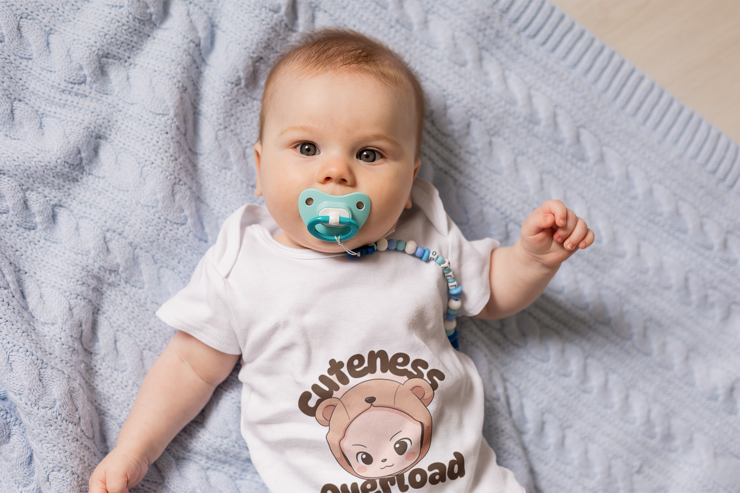 Happy baby in a Syntax Style Hub organic cotton bodysuit, lying comfortably on a soft blanket.